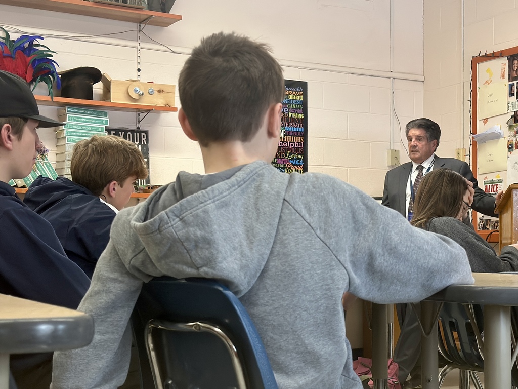 Students sit facing Senator Collamore as he speaks from the front of the classroom, viewed from behind one student in a gray hoodie.