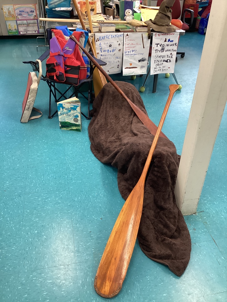 A classroom display with a life vest, paddles, a book, and a blanket.