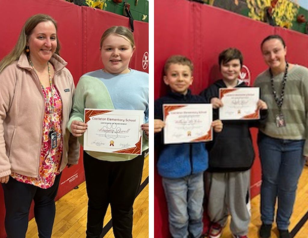 Two students hold certificates and stand with a staff member in a gymnasium, smiling against a red padded wall.