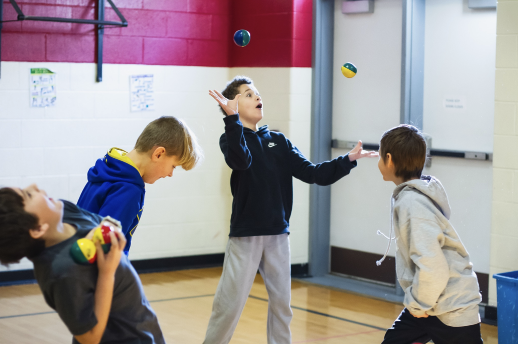 Group of students juggling small balls together during a hands-on circus skills session.