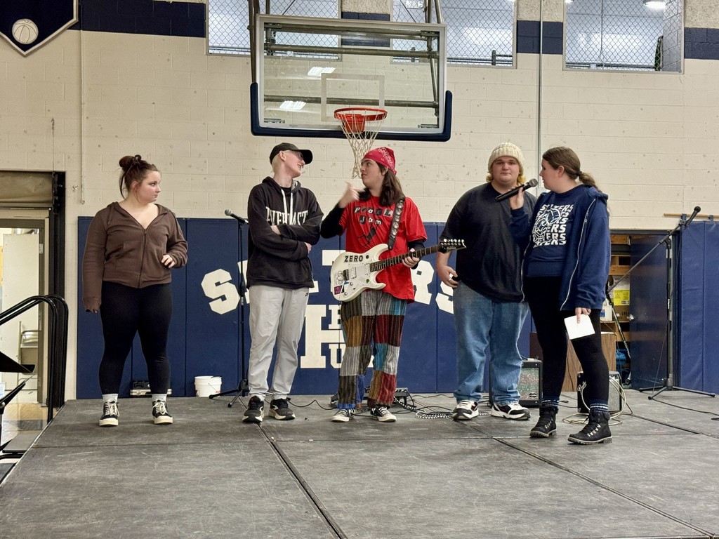 Four student performers pose together on stage after receiving awards, including first, second, third place, and the People’s Choice Award.