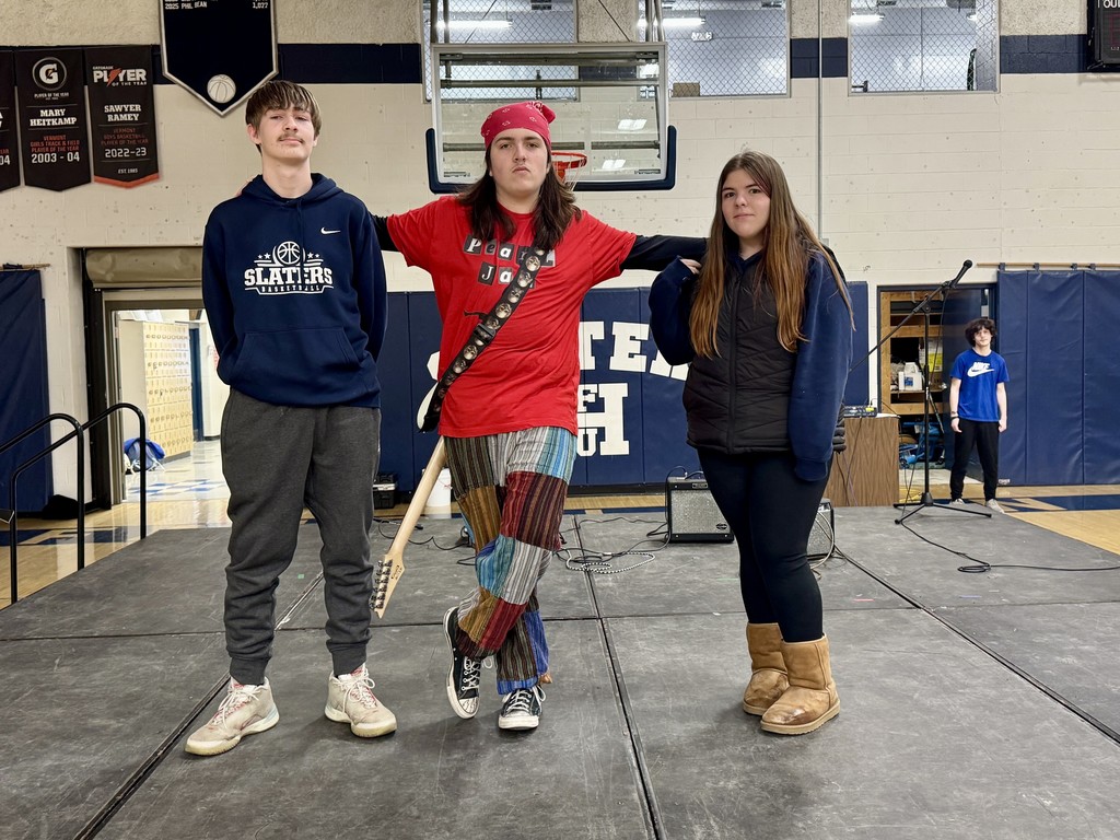 Members of the Modern Music class stand on stage, smiling and posing together after helping plan and organize the talent show.