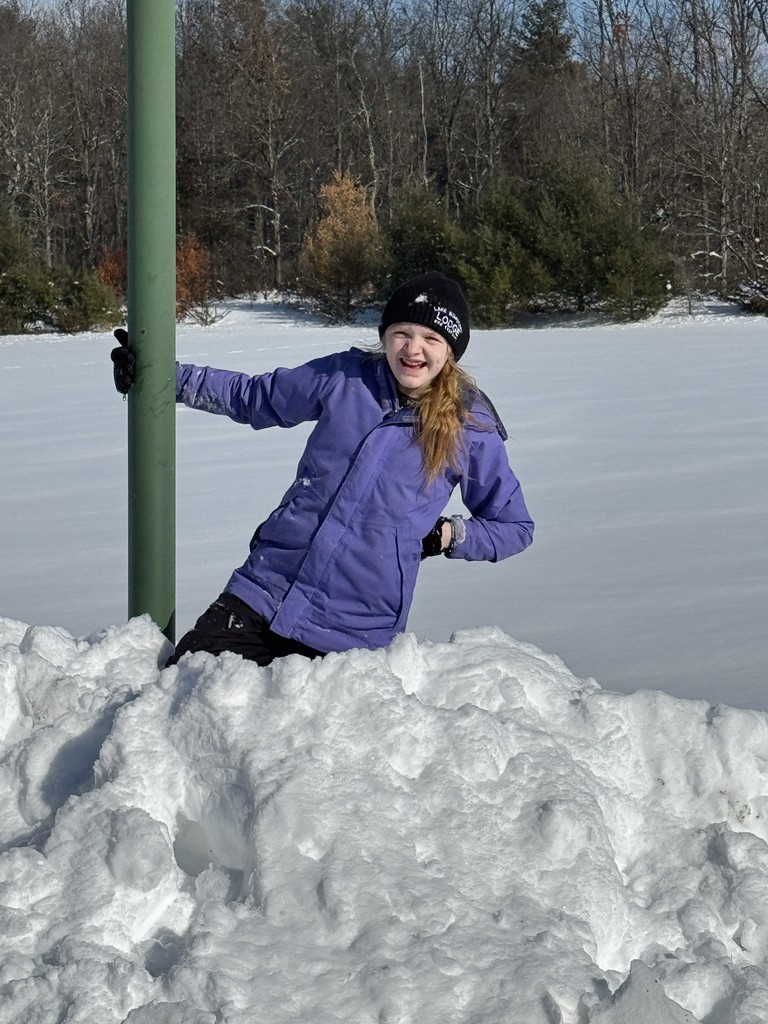 a girl in a purple jacket and pom-pom beanie