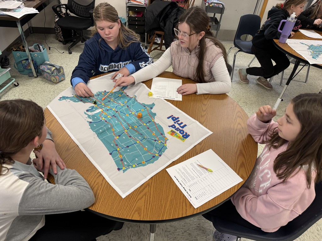 The Game Board: Students use a large fabric map of the United States featuring routes and state abbreviations to plan their journey.