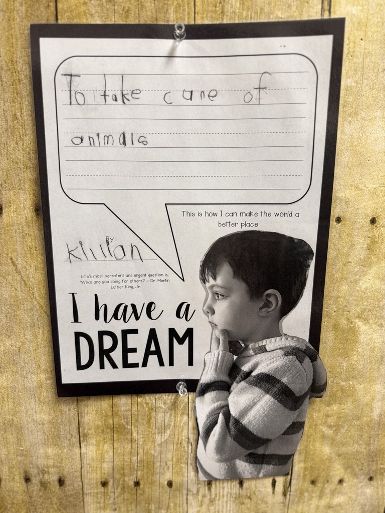 Black-and-white student portrait beside an “I Have a Dream” worksheet that reads, “To take care of animals,” displayed on a wood-style bulletin board.