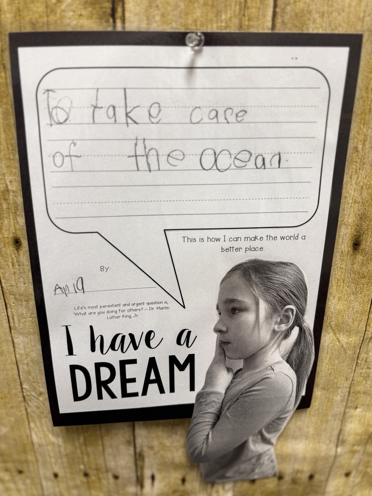 Black-and-white student portrait next to an “I Have a Dream” worksheet that reads, “To take care of the ocean,” pinned to a wood-pattern bulletin board.