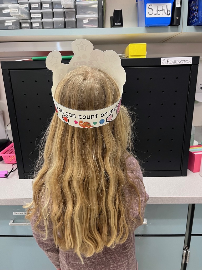 : The back view of the same girl from the previous photo, showing the back of the paper crown. The headband features the printed phrase "You can count on me!" decorated with small heart and dinosaur stickers.  