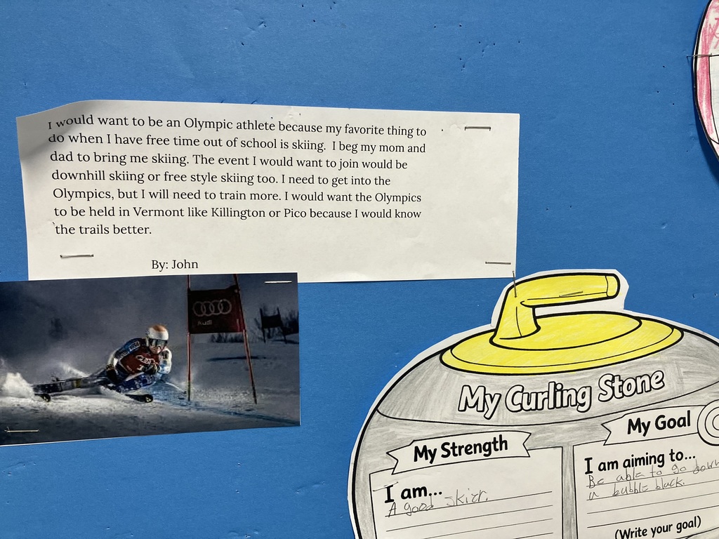 school project about Olympic dreams by a student named John.  The Essay: A typed paragraph where John expresses his desire to be an Olympic skier. He mentions his love for downhill and freestyle skiing and suggests the Olympics be held in Vermont at Killington or Pico because he knows those trails well.  The Graphics: A photo of a professional alpine skier in a race is pinned next to the essay.  The Worksheet: Below the essay is a "My Curling Stone" cutout. In the "My Strength" section, John wrote: "A good skier." In the "My Goal" section, he wrote: "Be able to go down a bubble black [diamond]."