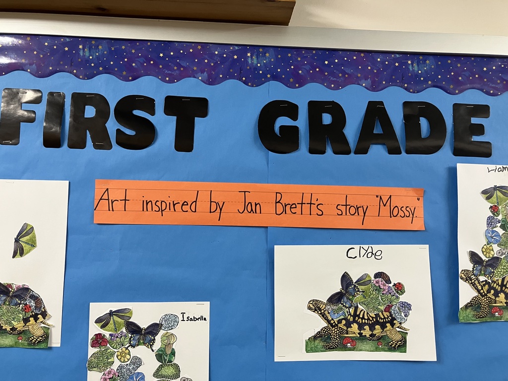  wide shot of the top section of the bulletin board, showing the "FIRST GRADE" header and the orange title strip. It features collages by students 