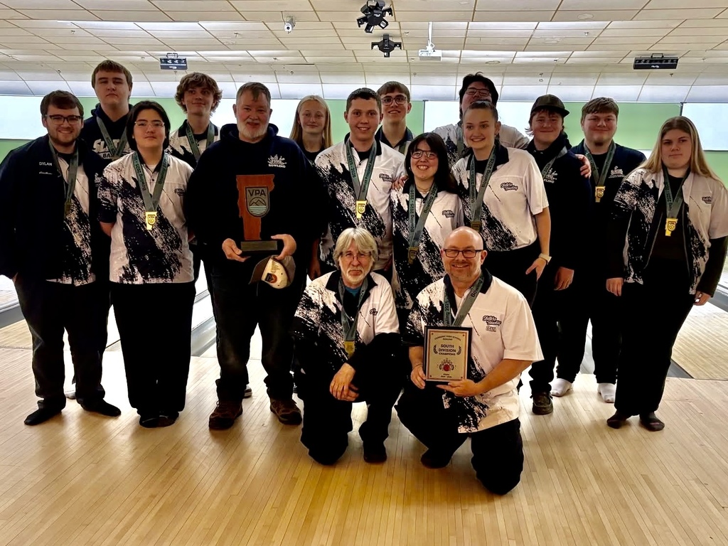The Fair Haven Slater bowling team poses together at a bowling alley with coaches in front, several athletes wearing medals and team jerseys while holding championship plaques and trophies.