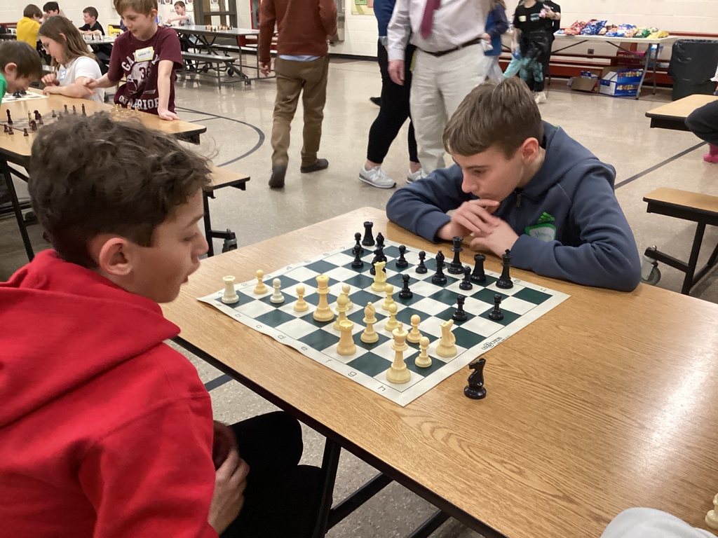 Two students face each other across a chessboard studying the position before making their next move during a chess tournament-style event.