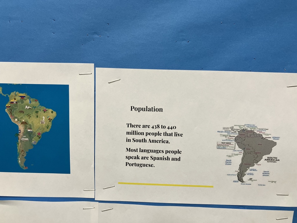  A close-up of a poster titled "Population" for South America.  Text: "There are 438 to 440 million people that live in South America. Most languages people speak are Spanish and Portuguese."  Visuals: A colorful map of South America decorated with icons (like a llama and a soccer ball) and a smaller gray political map.  Asia 
