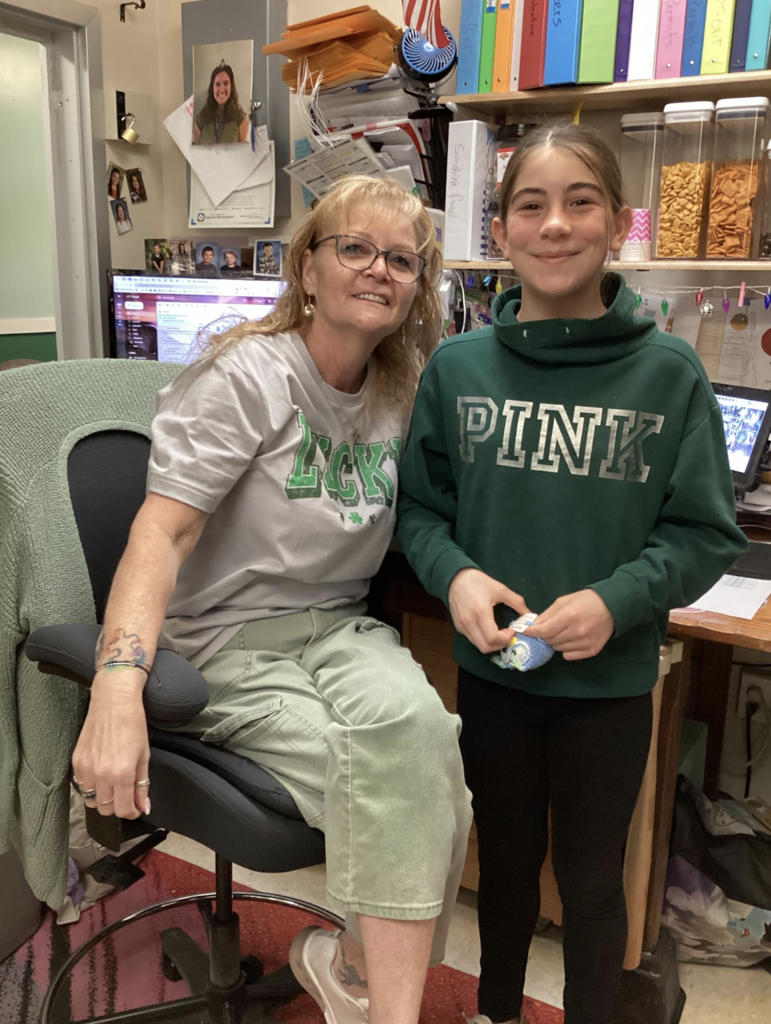 Staff member and student smile together in an office space.