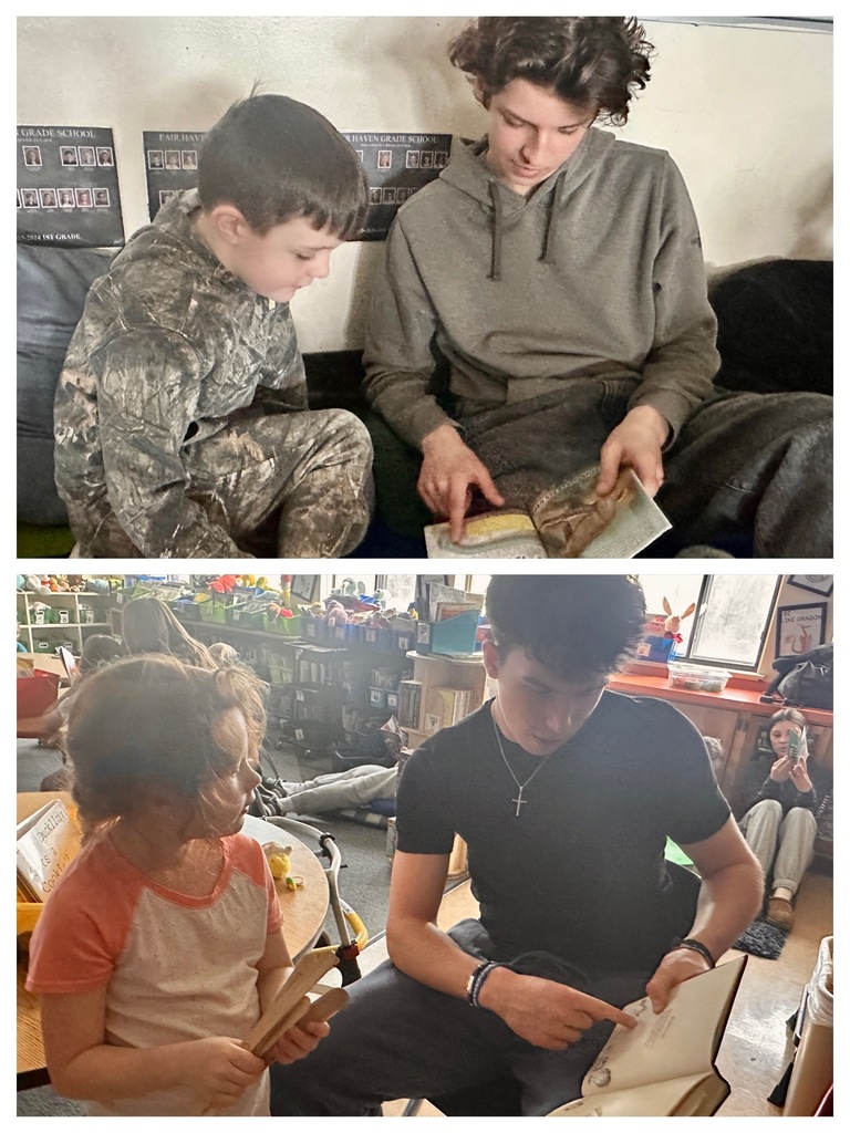 A high school student in a gray hoodie sits with a young boy in a camouflage outfit, both looking at and reading a book together on a couch.
