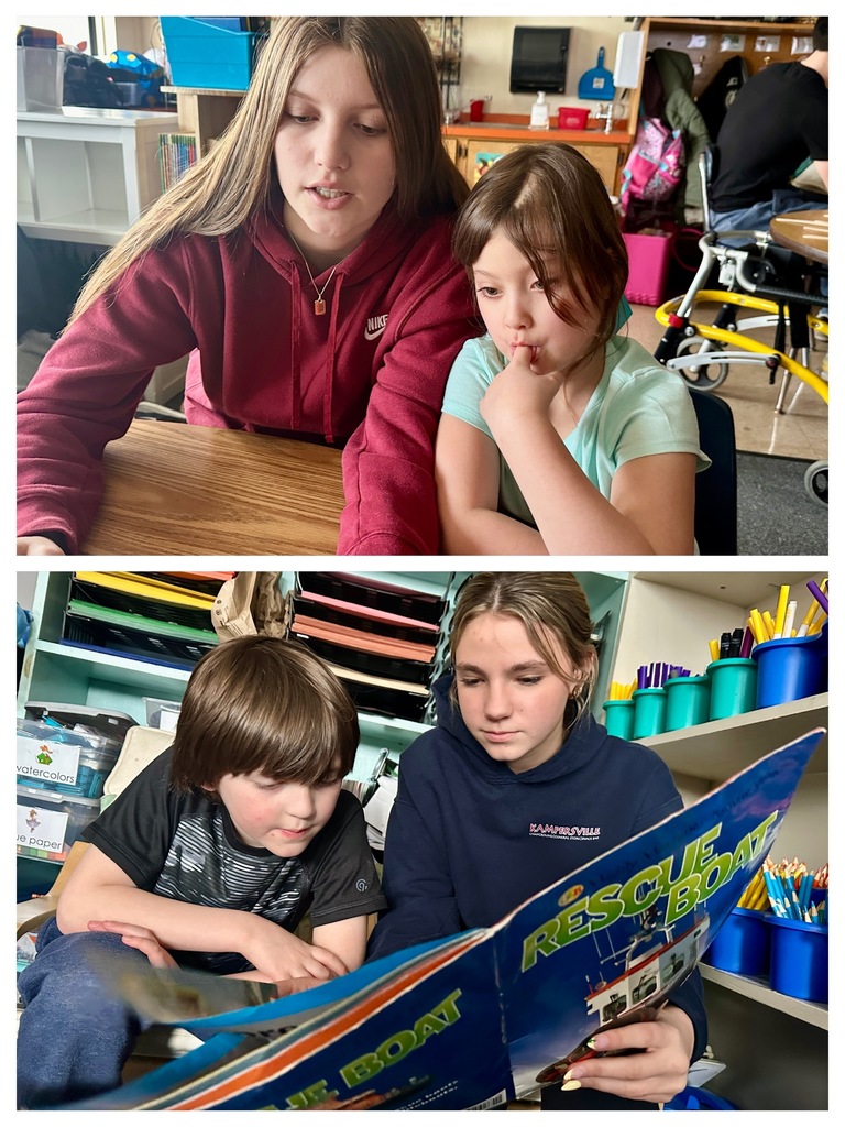 A high school student reads a colorful children’s book aloud while a young boy listens nearby in a classroom reading area.