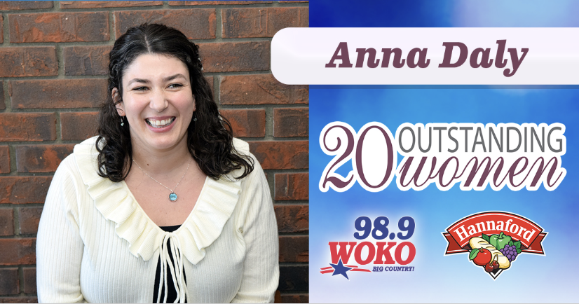 A graphic featuring a smiling woman, Anna Daly, seated in front of a brick wall, alongside text reading “20 Outstanding Women” with WOKO 98.9 and Hannaford logos displayed.