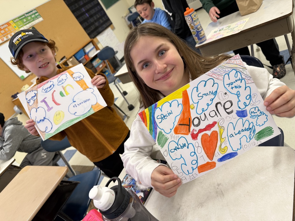 Two students hold bright drawings with positive messages such as “You are smart” and “I can do hard things,” surrounded by colorful doodles.