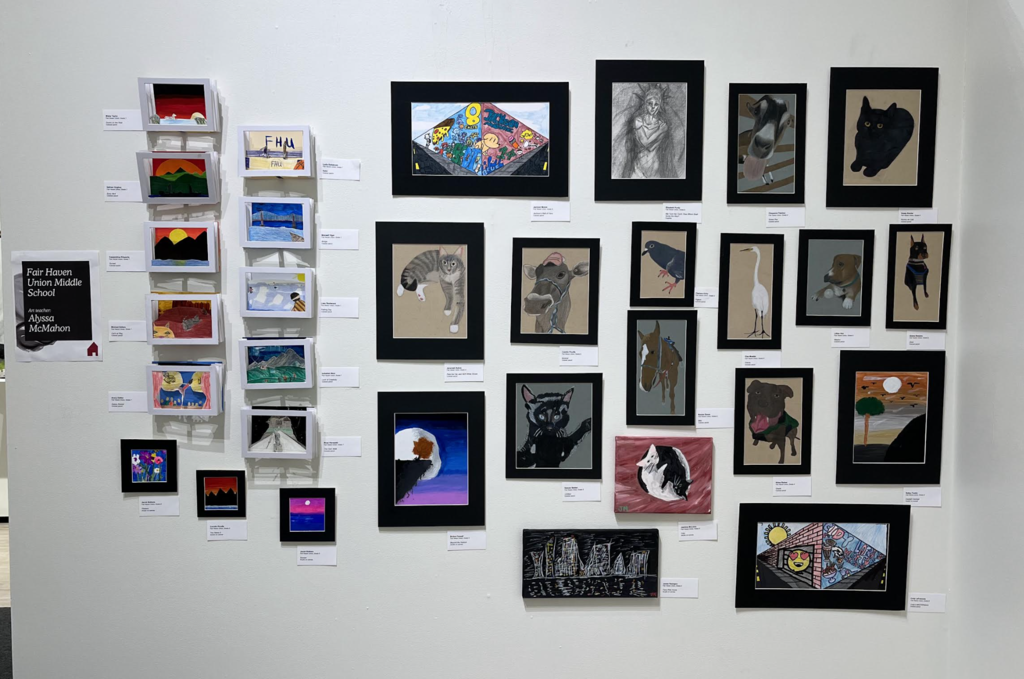 Gallery wall display featuring multiple student artworks, including drawings, paintings, and mixed media pieces labeled from Fair Haven Union Middle School.