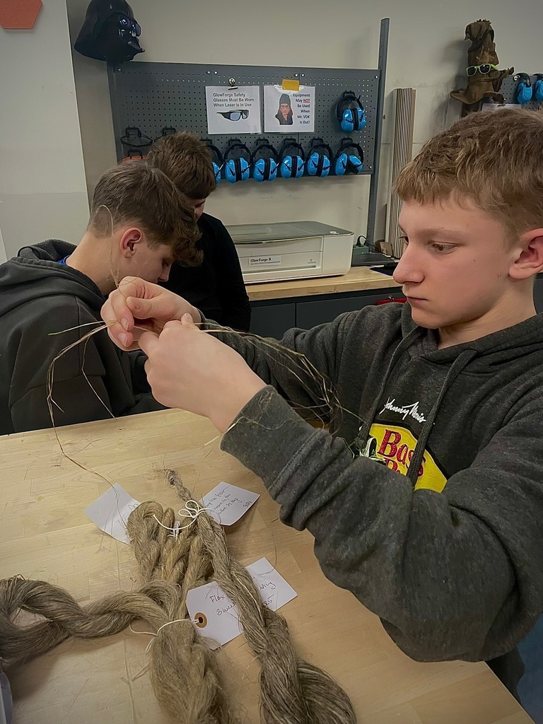 Middle school students in a classroom carefully working with plant fibers, twisting strands to create cordage.
