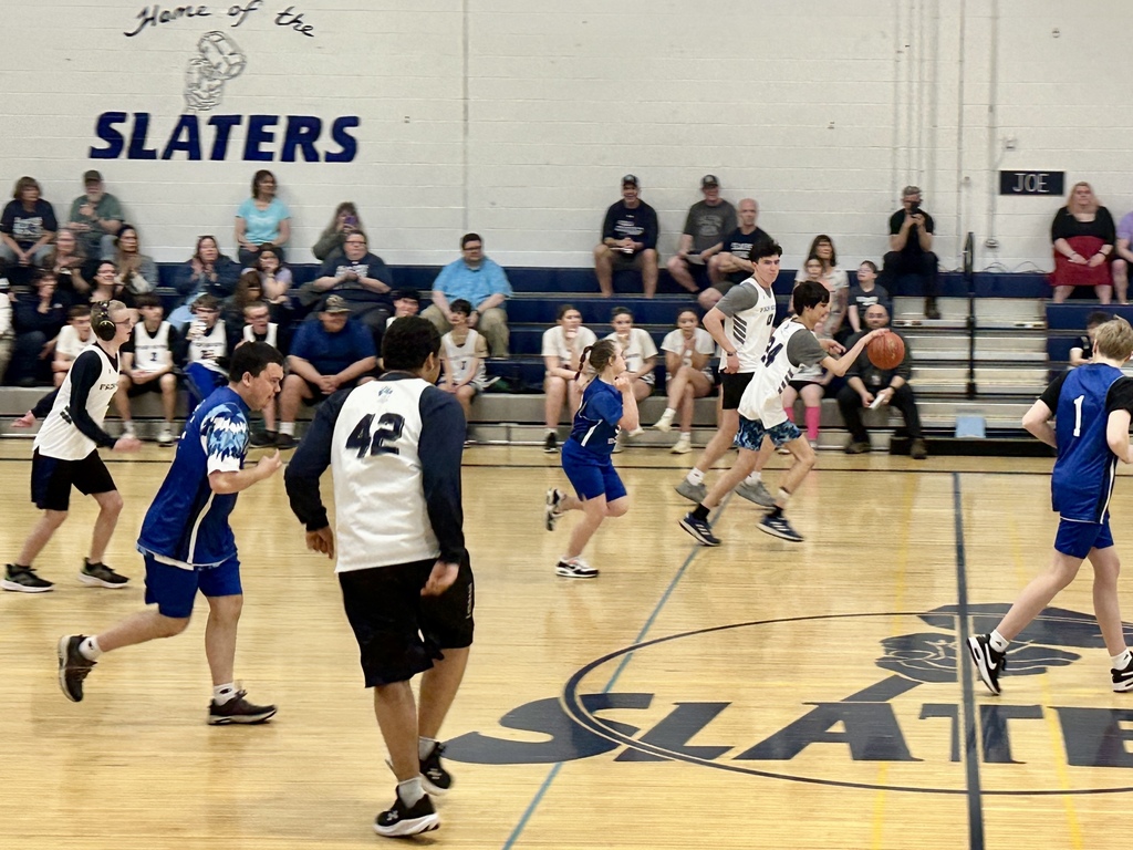 Players from both teams run down the court during a Unified Basketball game while spectators watch from the bleachers.