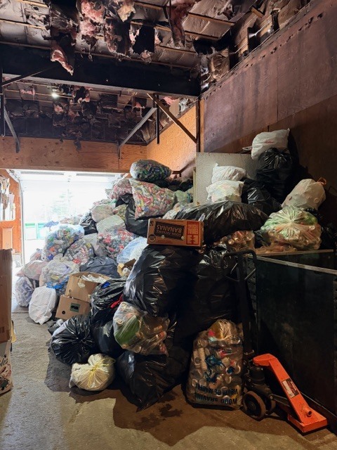 Interior space filled with large piles of bagged recyclables stacked against the wall, showing the scale of the collection effort.