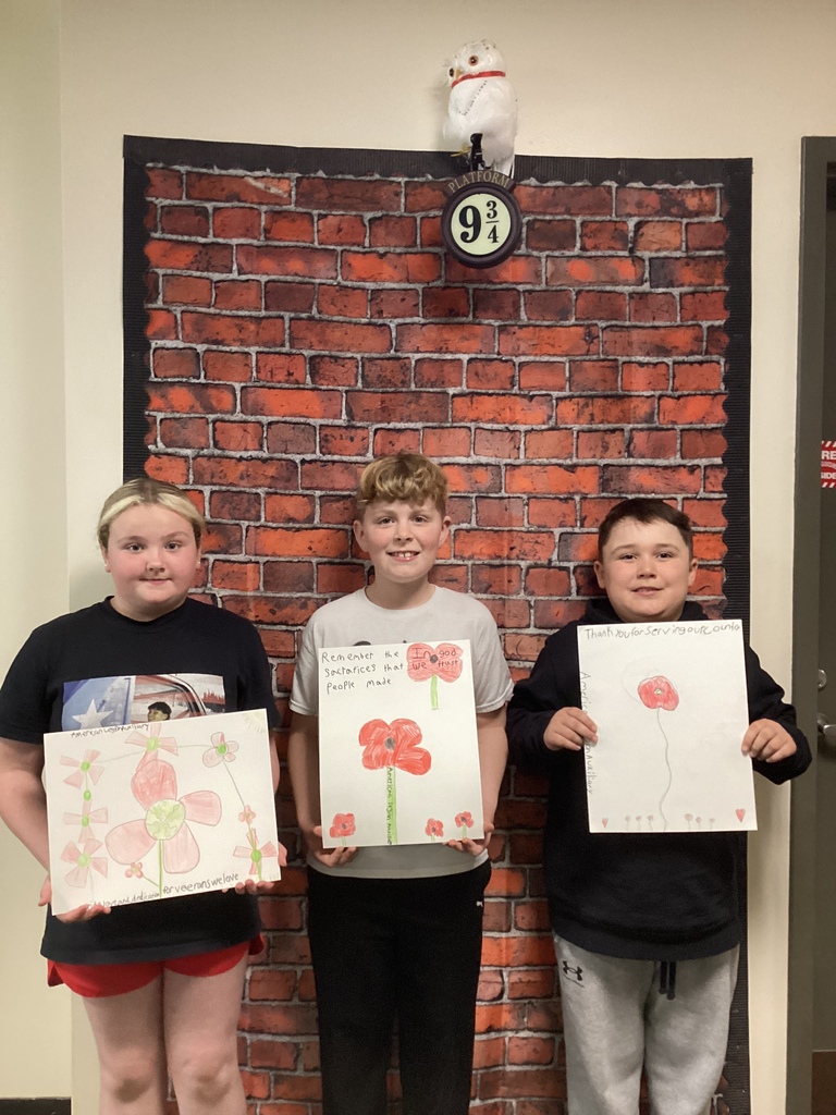 Three students display poppy posters with large red flowers and messages about sacrifice and service.