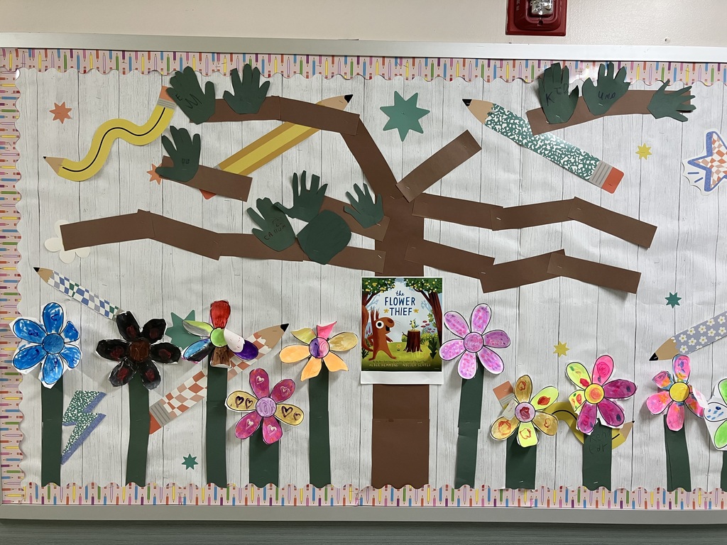 Book Cover Close-up A close-up shot of a printed book cover for "The Flower Thief" by Alice Hemming and Nicola Slater.  Characters: The illustration features a whimsical, bright orange squirrel with large, expressive eyes looking toward a small, yellow and blue bird perched on a tree stump.  Setting: They are in a lush green meadow under a bright blue sky, framed by two large trees with green leaves and small yellow fruit or flowers.  Text: The title "the FLOWER THIEF" is written in bold, blue playful lettering at the top. At the bottom, it reads: "By the New York Times bestselling creators of The Leaf Thief, ALICE HEMMING & NICOLA SLATER."