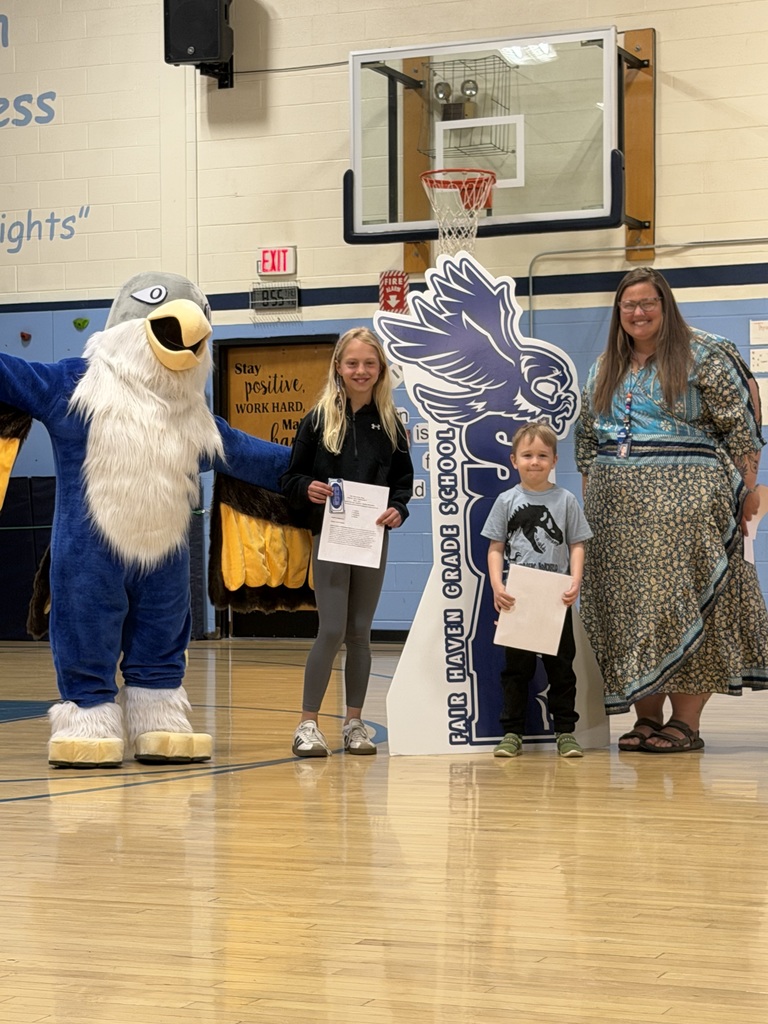 Twostudents holding certificates and one adult posing with a blue eagle mascot in a gymnasium in front of a "SOAR" sign.