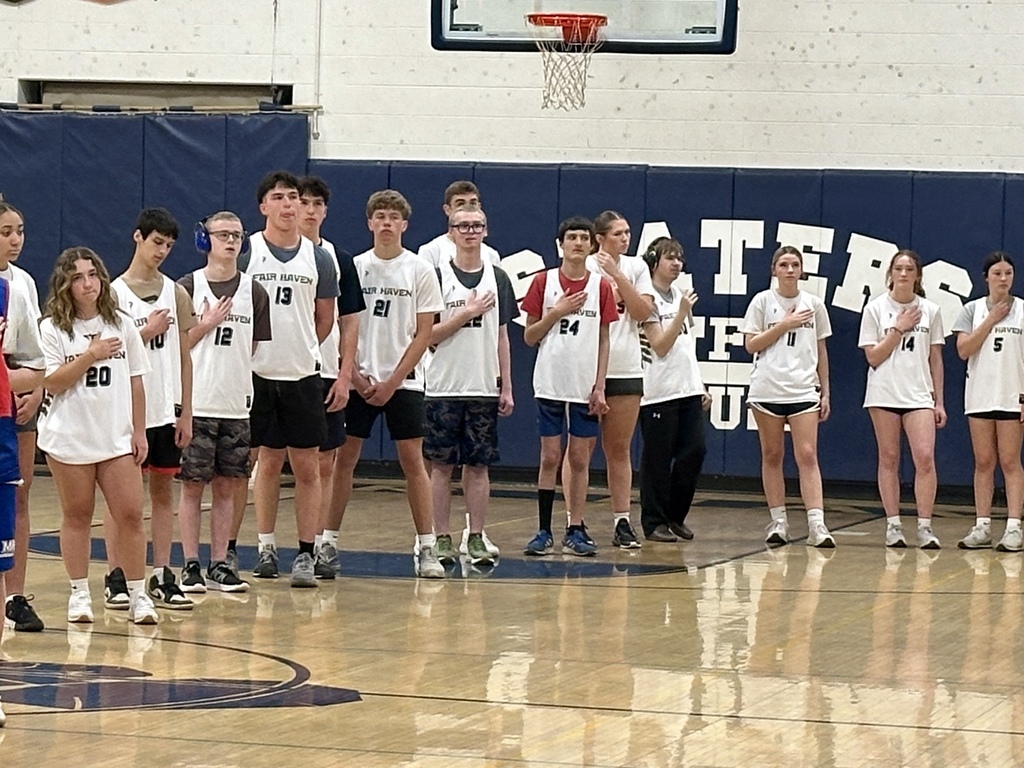 The Fair Haven Unified team stands in a line on the court with hands over their hearts, likely during the national anthem, facing the same direction.