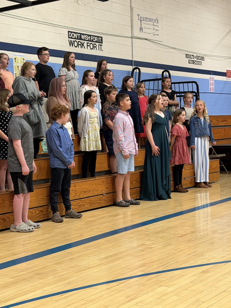 FHGS students sing together on risers during the spring concert while audience members watch from the gymnasium seating area.