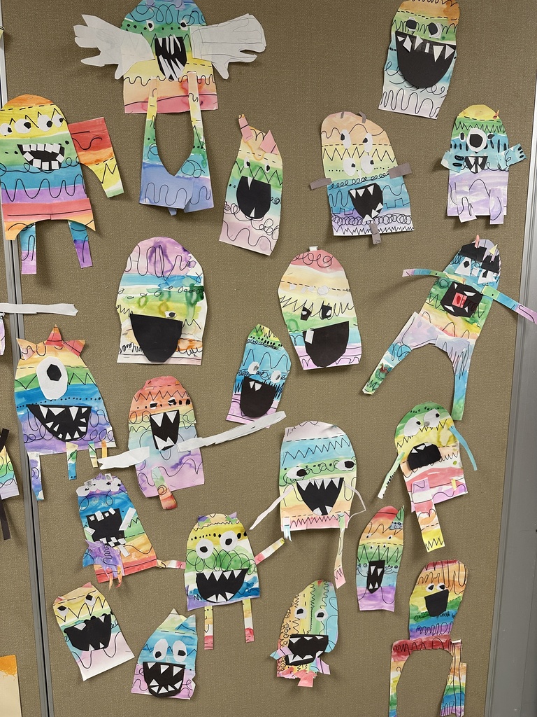 Alt text: A display board features colorful student-created monster artwork made with rainbow patterns, bold shapes, and playful facial expressions.