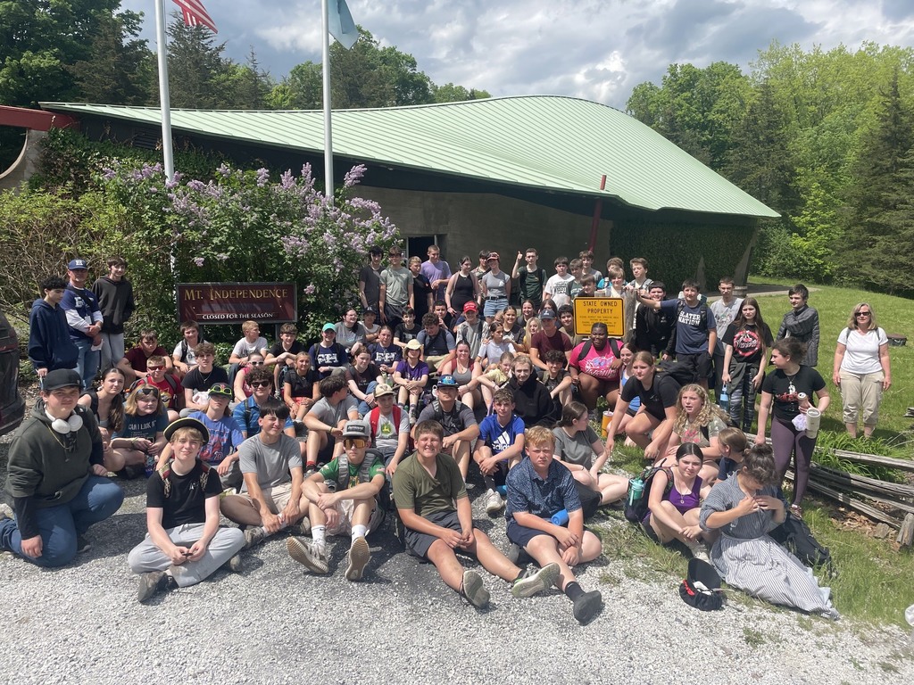 A large group of 8th grade students and staff gather outside near the Mount Independence sign for a class photo at the conclusion of their field trip.