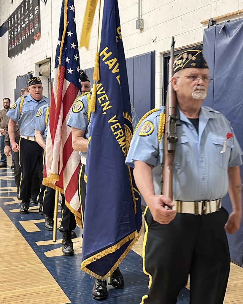 Members of the Fair Haven American Legion Post 49 Color Guard march into the gymnasium carrying flags and ceremonial rifles during the Memorial Day ceremony.