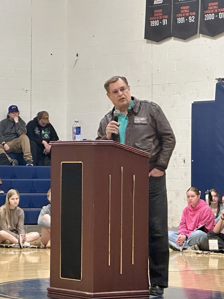 Guest speaker Mr. Greg Parke, a retired United States Air Force Lieutenant Colonel, stands at a podium speaking to students and staff during the Fair Haven Union Middle & High School Memorial Day program.