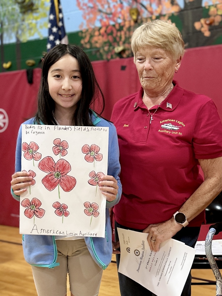 A student proudly holds a poppy-themed poster next to an American Legion Auxiliary member after being recognized during the Memorial Day assembly.