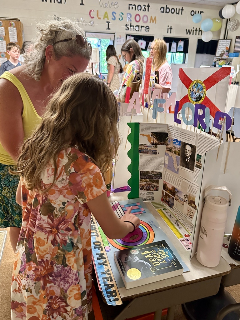 A student and family member stand beside a colorful classroom display board featuring a Florida-themed project and student work.