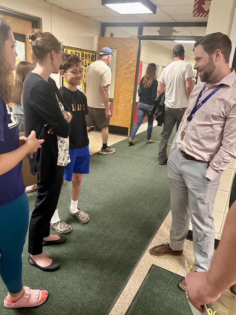 A teacher speaks with students and family members in a school hallway filled with visitors attending Castleton Elementary School’s Celebration of Learning.
