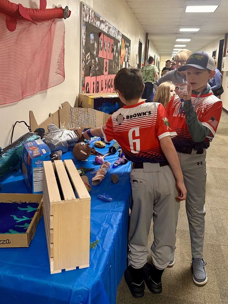 Two students in baseball uniforms explore a display table filled with creative student-made projects and recycled art during Castleton Elementary School’s Celebration of Learning.