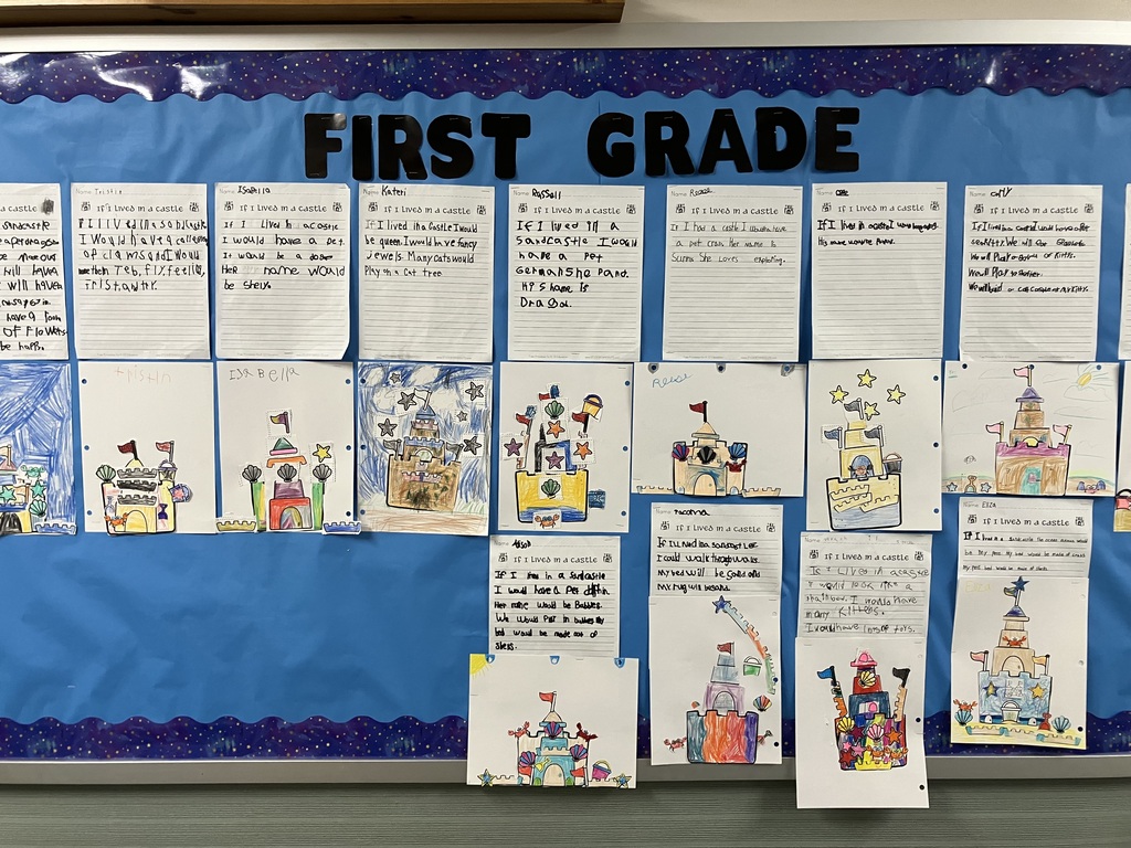  A wide shot of a primary school classroom bulletin board with a dark blue background and a scalloped, glittery purple border. Large black cutout letters at the top center spell out "FIRST GRADE." Below the heading, multiple rows of lined student writing papers are displayed, each paired with a colorful, hand-colored drawing or cutout collage of a sandcastle. The writing prompts are titled "If I Lived in a Castle," featuring young children's handwriting and phonetic spelling.  IMG_3332.jpg Alt Text: A close-up view of a first-grader's schoolwork on a blue background. The top page shows handwritten text by a student named Kateri, reading, "If I lived in a castle I would be queen. I would have fancy jewels. Many cats would play on a cat tree." Below the writing is a drawing of a multi-tiered brown sandcastle heavily colored in with crayons. The background is filled with messy, dark blue and black scribbles representing a stormy or night sky, decorated with several cutout paper stars glued around the castle. 