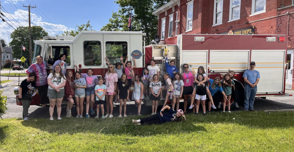 Students and chaperones pose in front of a Fair Haven fire engine outside the Fair Haven Fire Department during a community visit.