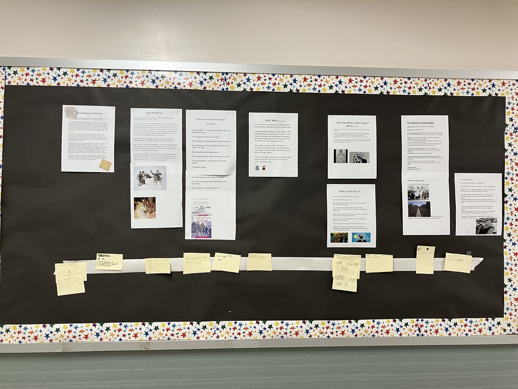 A close-up photograph of a student-written research paper titled "The Underground Railroad" by Hannah Parker, stapled to a black bulletin board. The paper features clip art of vintage newspaper clippings in the top left corner and a yellowed historical document in the bottom right corner.  The typed text includes paragraphs explaining that the Underground Railroad was not an actual railroad underground, but a network that included steamboats, wagons, and foot travel to help enslaved people escape to free states between 1830 and 1865. It mentions Henry "Box" Brown escaping in a box on March 29, 1849. It lists free states in the 1830s and 1860s, and discusses Abraham Lincoln's Emancipation Proclamation taking effect on January 1, 1863. It concludes by naming important figures like Harriet Tubman, Frederick Douglass, and William Lloyd Garrison.  IMG_3338.jpg Alt Text: A close-up photograph of a section of a black bulletin board featuring two columns of student work.  Left Column: A paper titled "Henry Box Brown" by Aubrey. The text describes how Henry was born into slavery, worked in a tobacco factory, and had his wife and children sold away. It explains how he escaped slavery by mailing himself in a box to a place without slavery. Below the text are two printed images: a historical illustration of Henry Box Brown emerging from his shipping crate, and a modern photograph of a historical reenactment showing a woman and child in 19th-century attire.  Right Column: A two-page paper titled "What was the Underground Railroad?" by RosaLee. The top sheet lists short, bullet-style facts stating that the Underground Railroad helped slaves escape from the 1830s until 1861, and that safe houses were used to keep people hidden. The bottom sheet features two small images: a historical drawing of men loading a boat, and the book cover for We The People: The Underground Railroad by Yona Zeldis McDonough. 