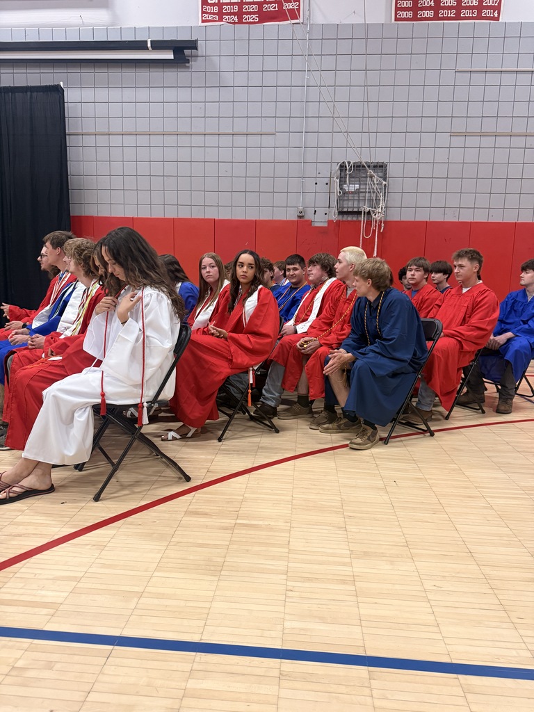 Students in red, white, and blue graduation gowns sit in rows of chairs inside a gymnasium during the Stafford Technical Center awards ceremony.
