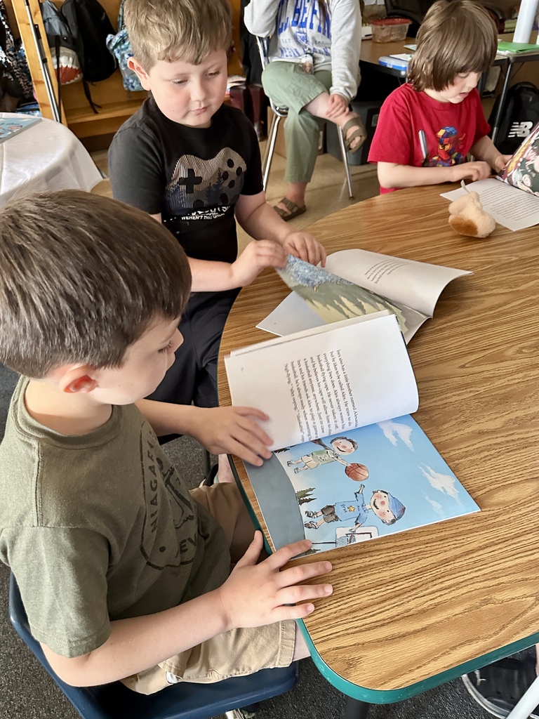 Two students flip through the pages of Inex & Alex, examining the illustrations and text together.