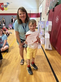 Student holds a certificate and smiles with a staff member during a school recognition event.