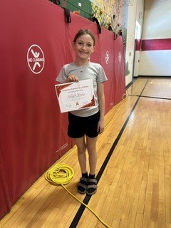 Student smiles while holding a certificate during a school recognition ceremony.