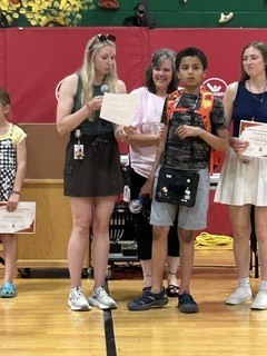 A student receives a certificate during an awards presentation while standing with school staff members.