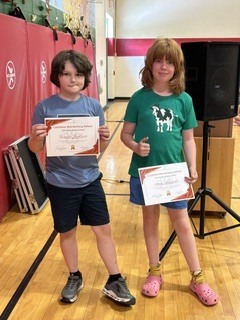 Two students pose with certificates after being recognized during a school celebration.
