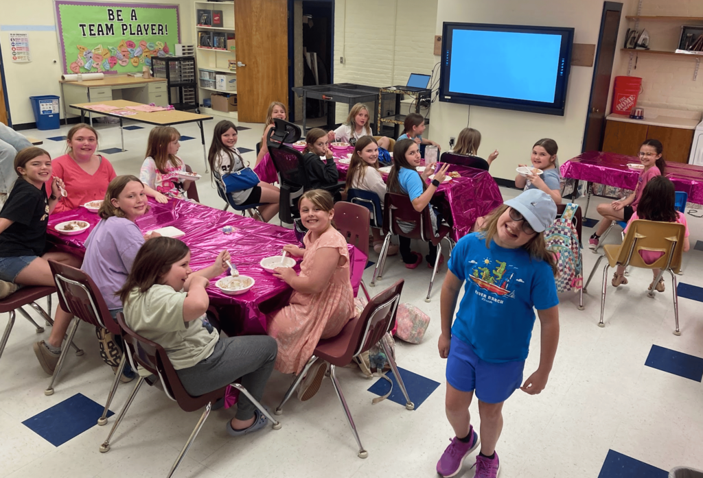 Girls on the Run participants sit around tables covered with bright pink tablecloths while enjoying ice cream and refreshments during the end-of-season celebration.