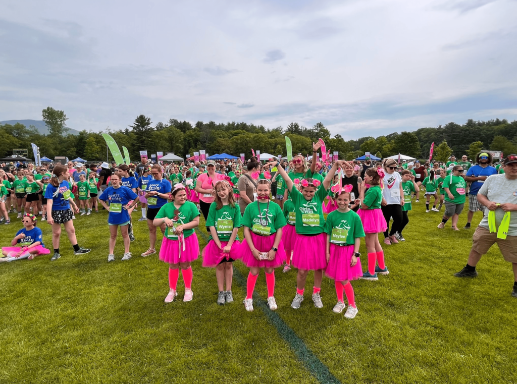 Girls on the Run participants gather with teammates and coaches among a large crowd of runners and families before the start of the celebratory 5K.