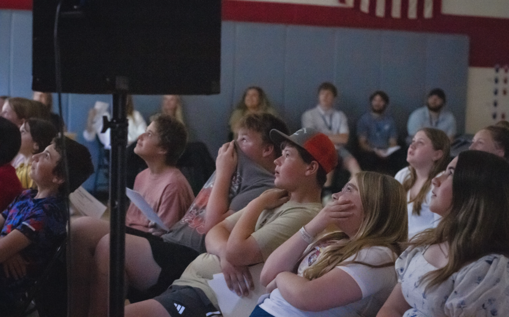 Students sit together watching the end-of-year slideshow, reflecting on their journey from childhood to sixth grade during the Castleton Elementary School Torch Ceremony.